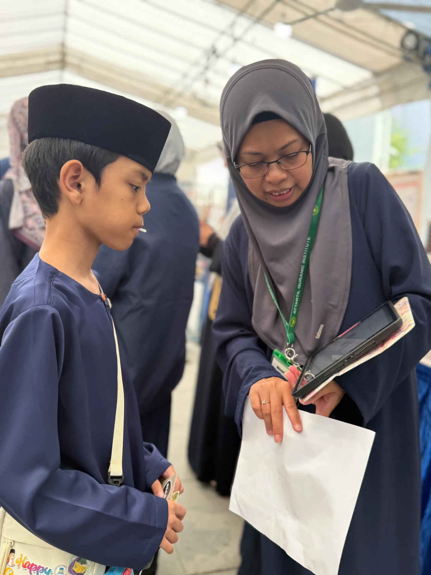A teacher explaining Qur'anic learning to a boy at the festival