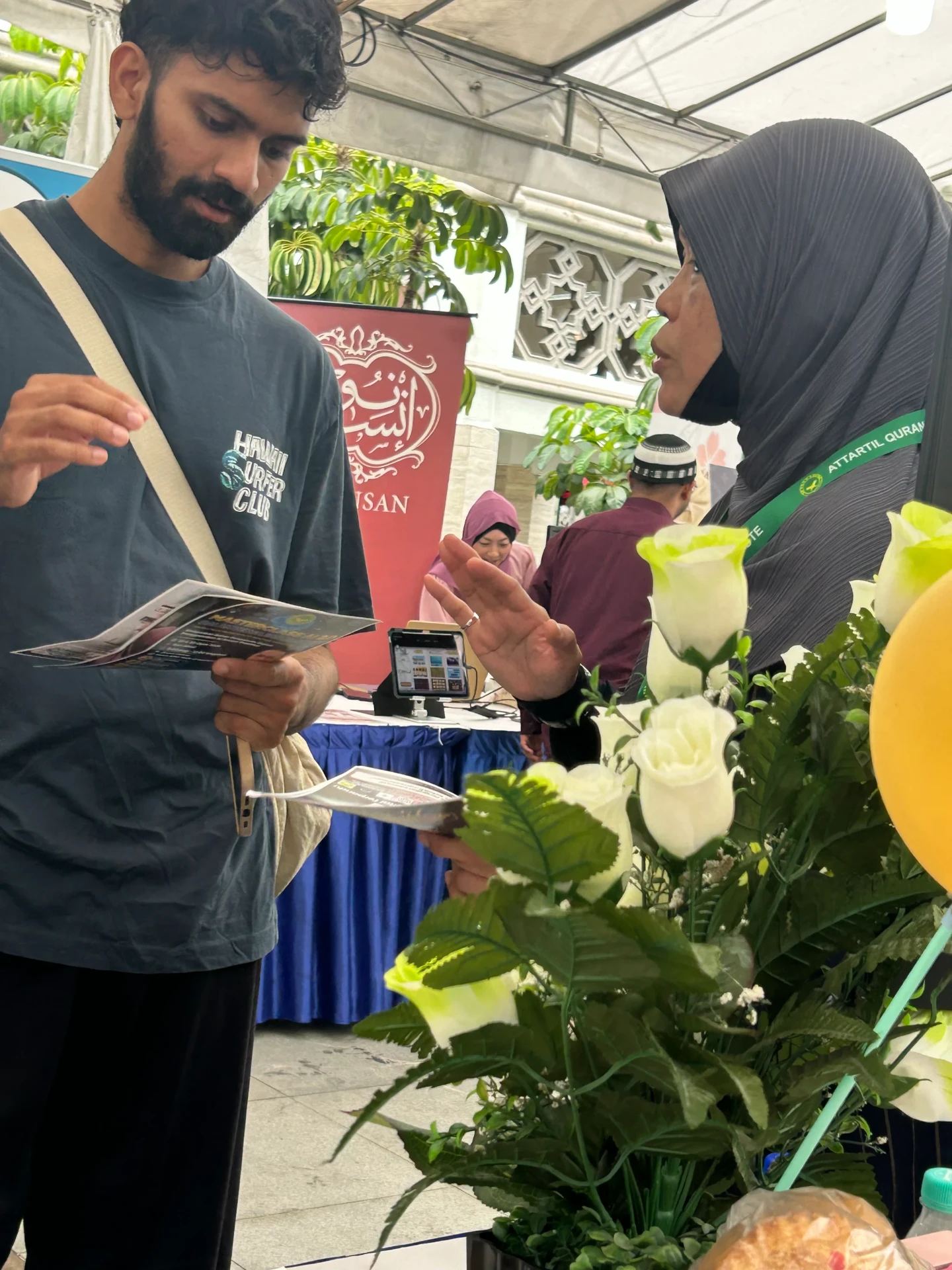 A volunteer sharing the Masterclass AI flyer with a visitor