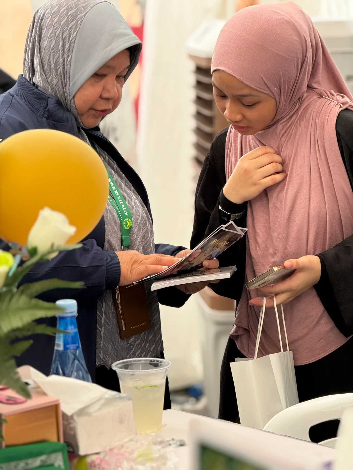 An AtTartil QI volunteer showing programme brochures to a young visitor