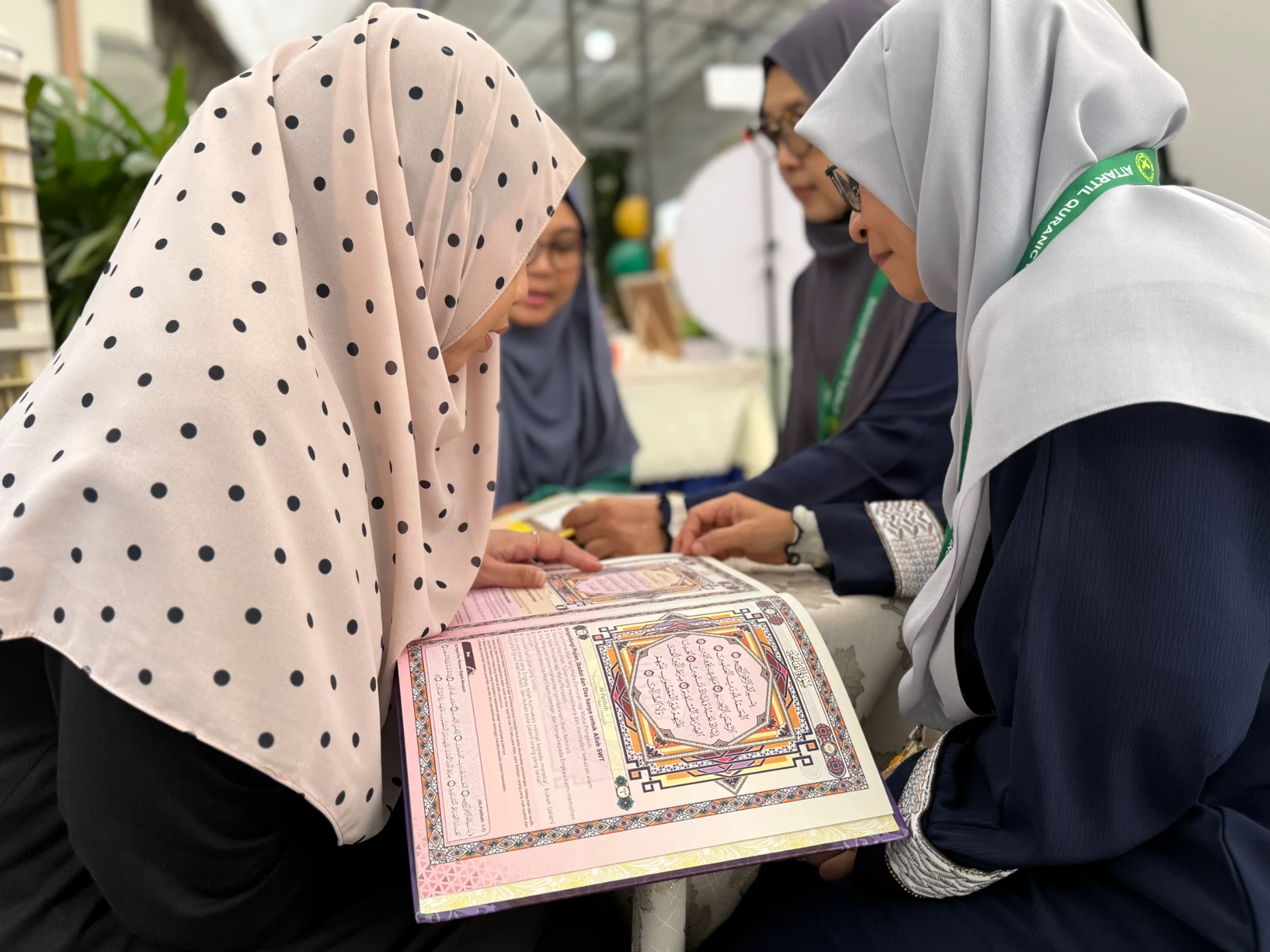 Visitors reading an illuminated Qur'an with AtTartil QI teachers at the festival