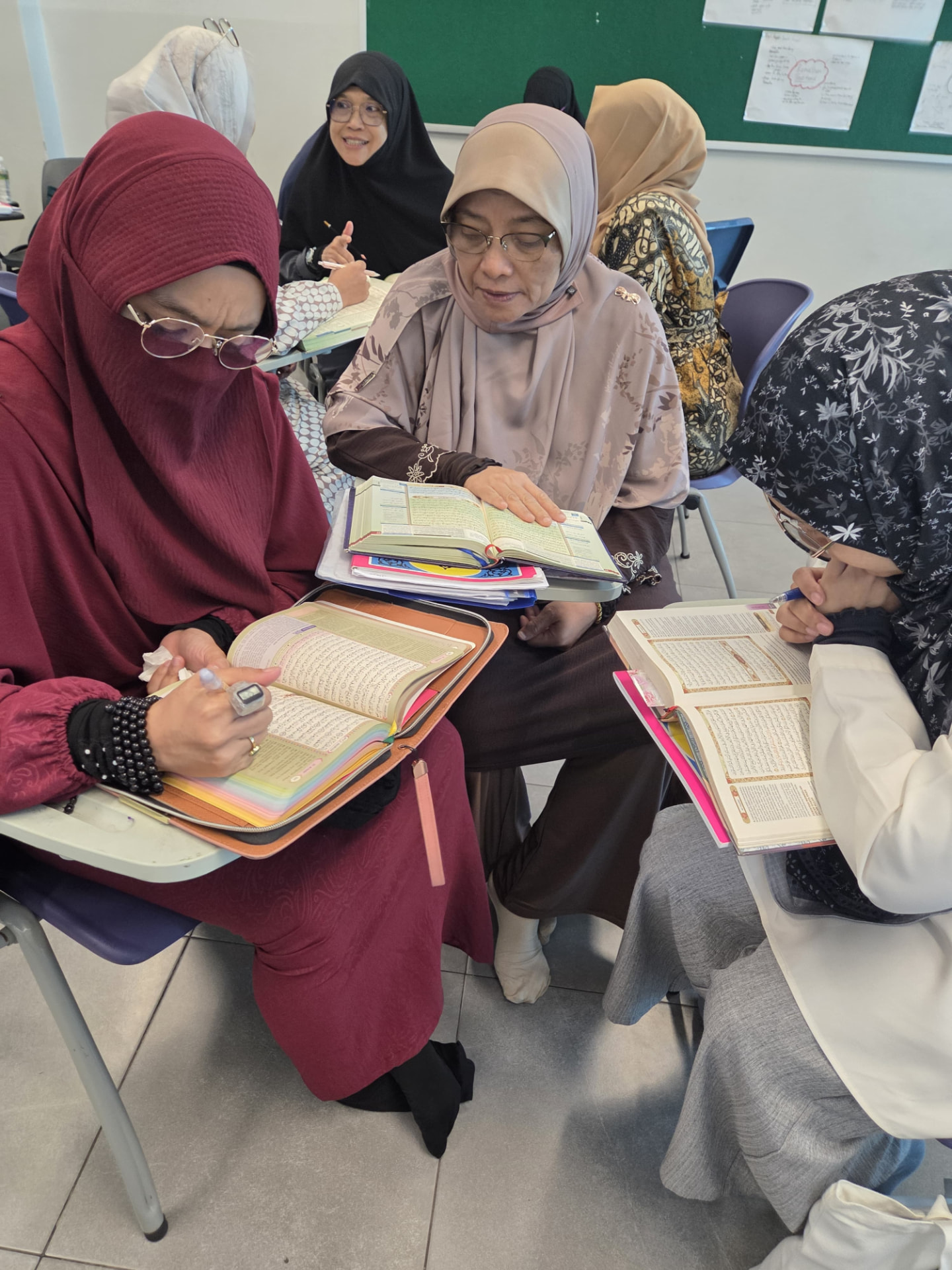 Adult students studying the Qur'an together in a small group during class