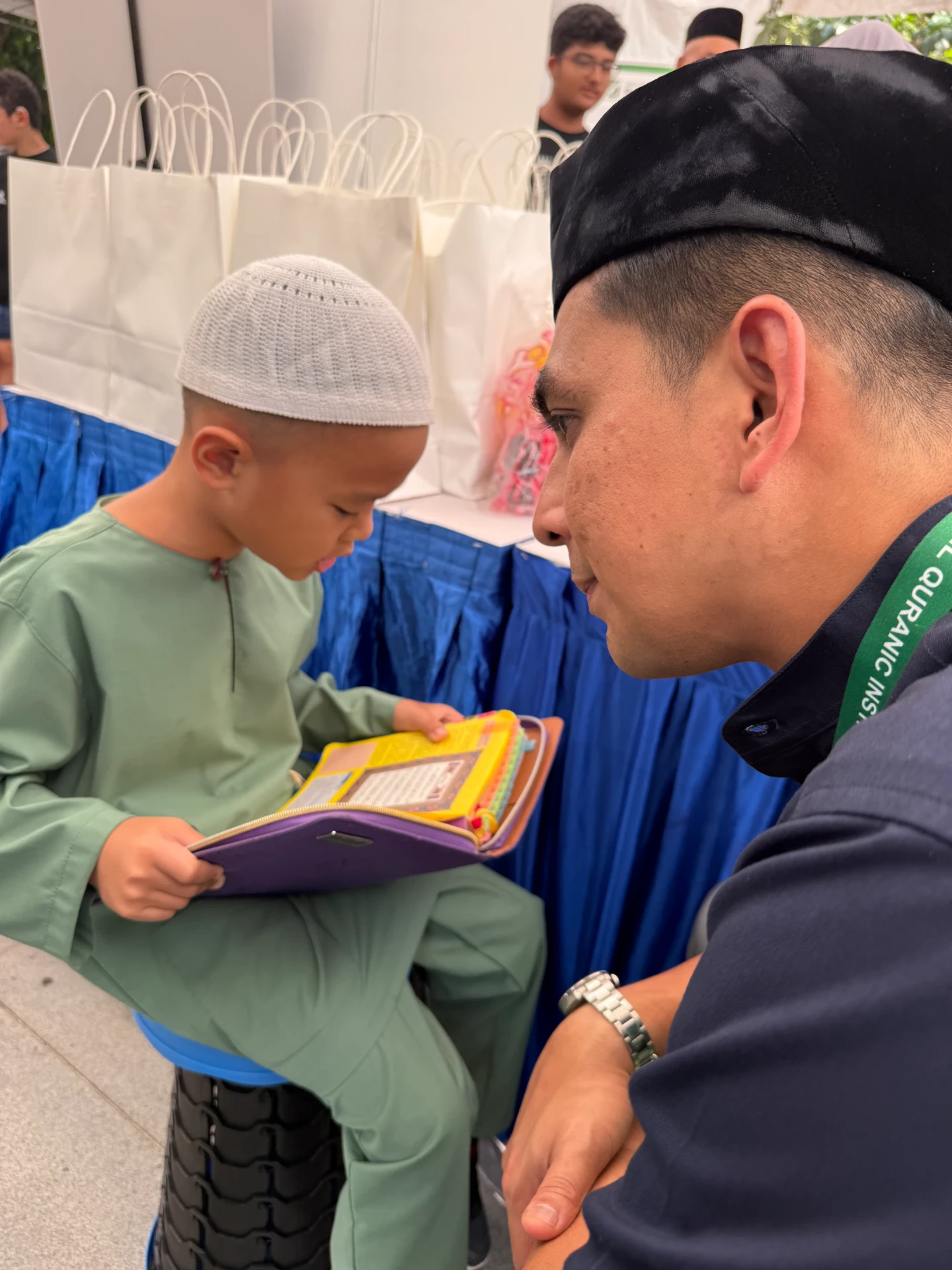 A young boy reading with an AtTartil QI teacher at Quran Festival 2026