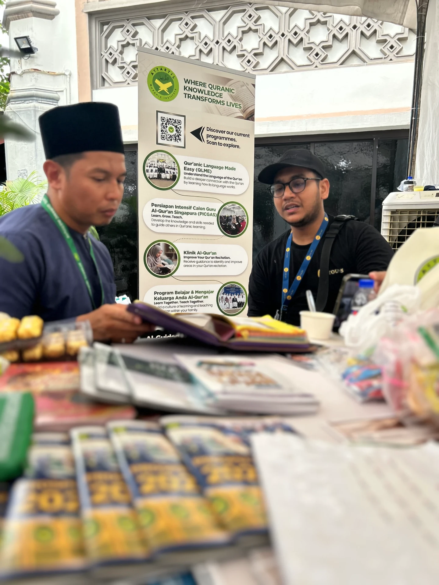 Visitors speaking with an AtTartil QI teacher at the booth