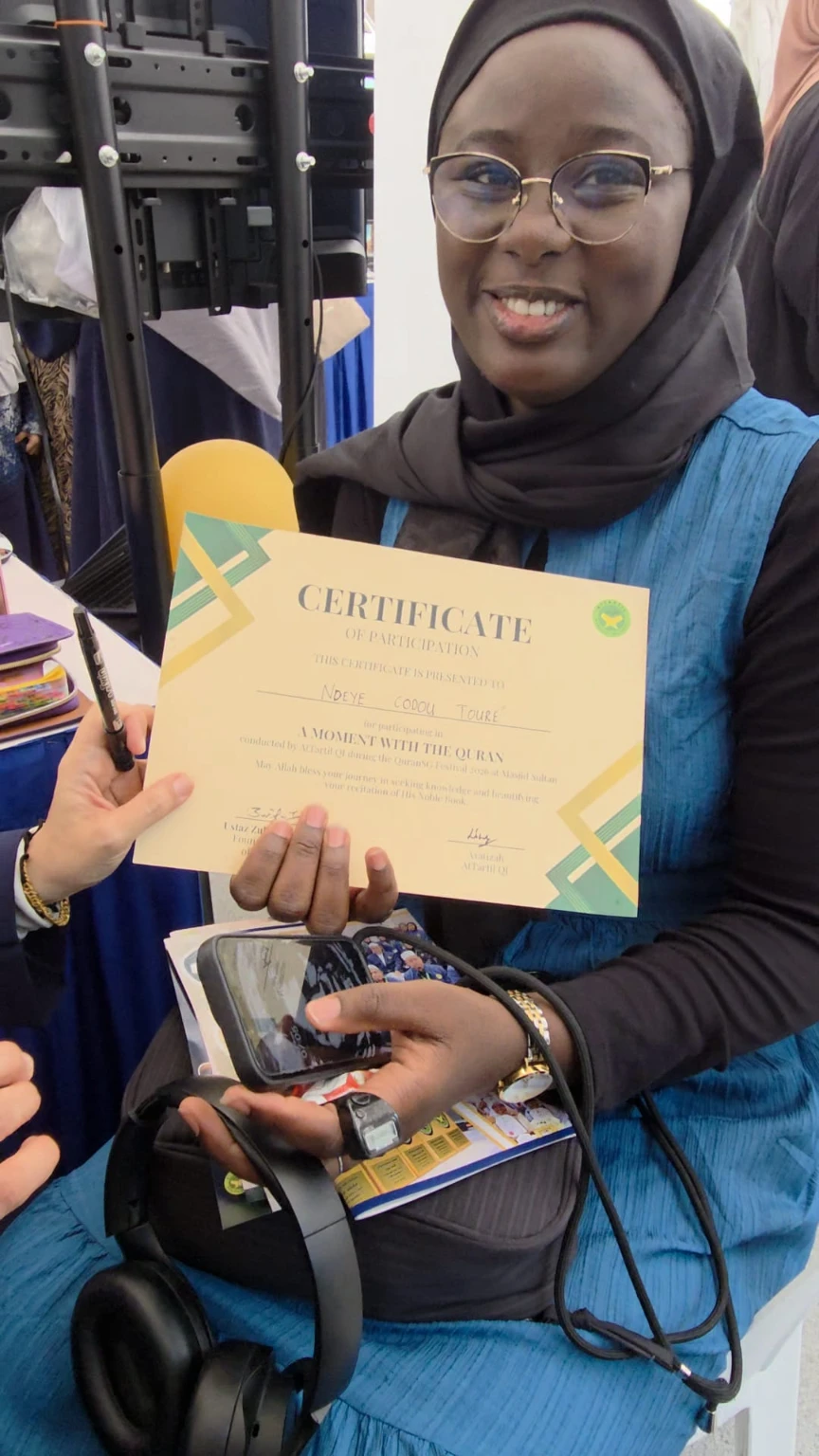 A participant smiling with her 'A Moment With The Quran' certificate