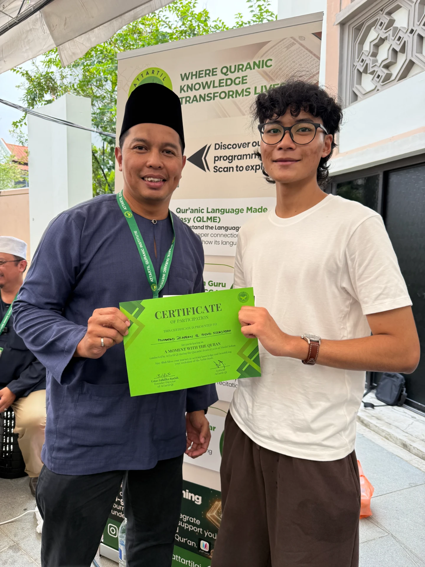 A teenage participant receiving his certificate from an AtTartil QI teacher