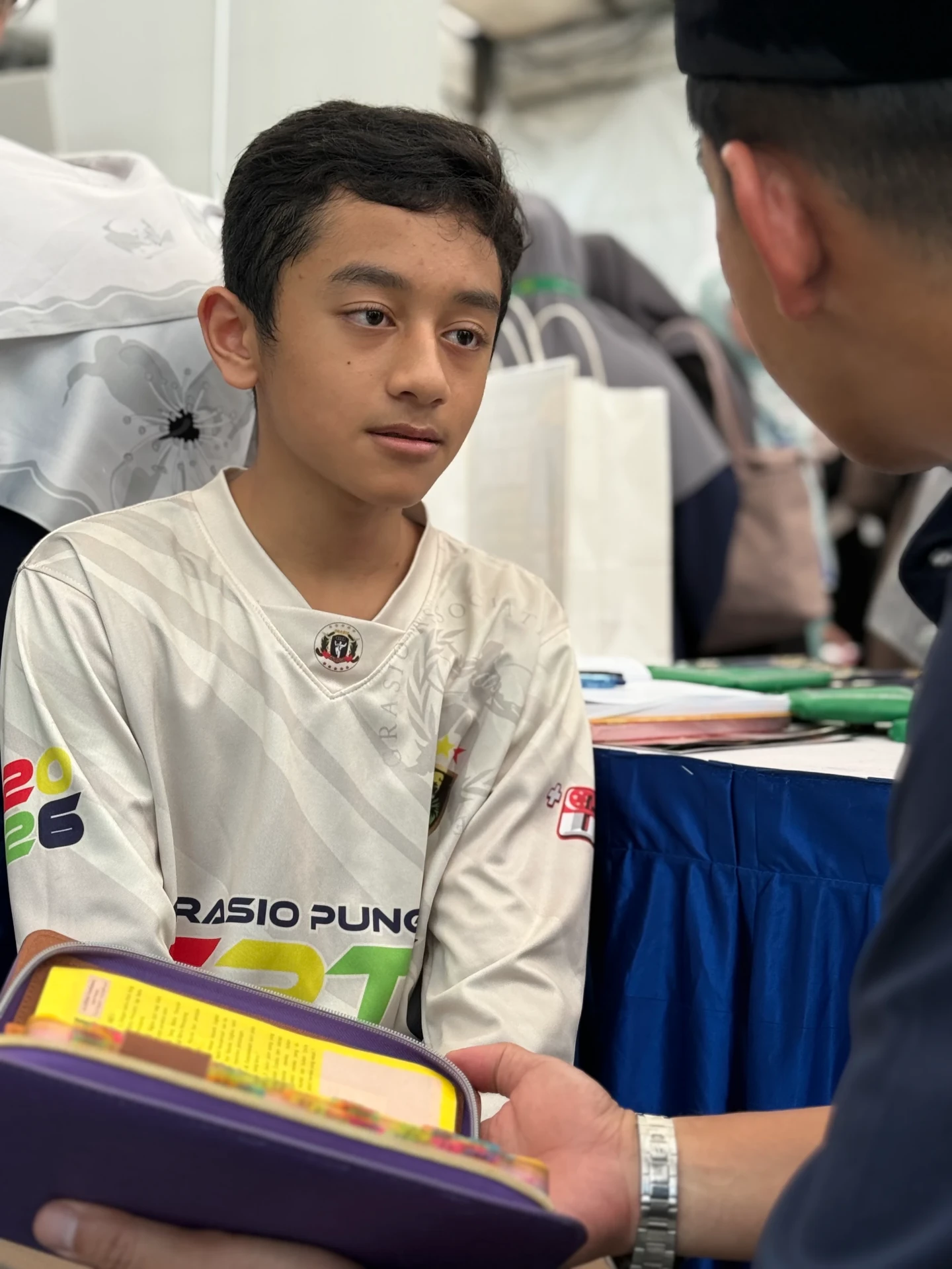 A teenage boy listening attentively to an AtTartil QI teacher at the booth