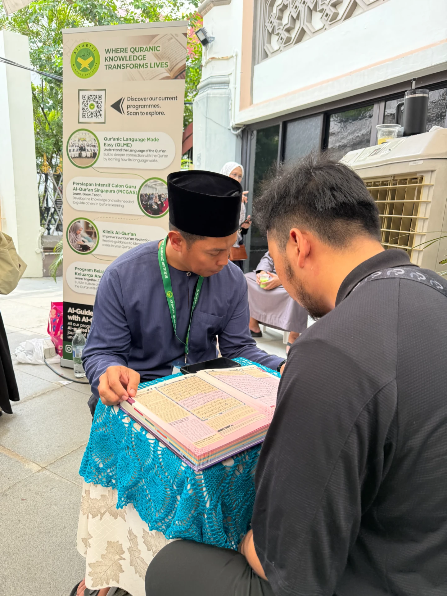 An AtTartil QI teacher guiding a visitor through a Qur'an recitation