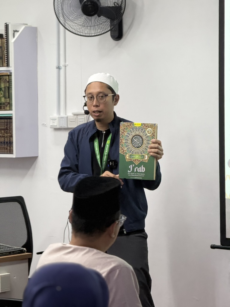 A QLME Batch 23 teacher presenting an I’rab Al‑Quran Per Kata reference book during the first session